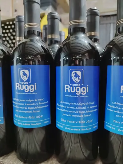 Garrafas de vinho tinto com rótulo azul do Grupo Ruggi e mensagem de boas festas