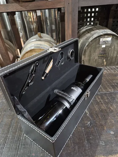 Estojo de couro preto com garrafa de vinho e acessórios de sommelier