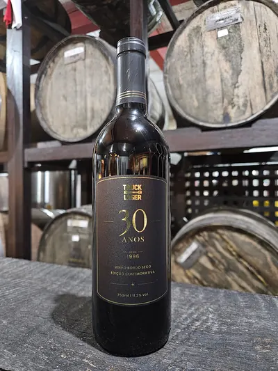 Garrafa de vinho com rótulo preto e dourado comemorando os 30 anos de uma empresa